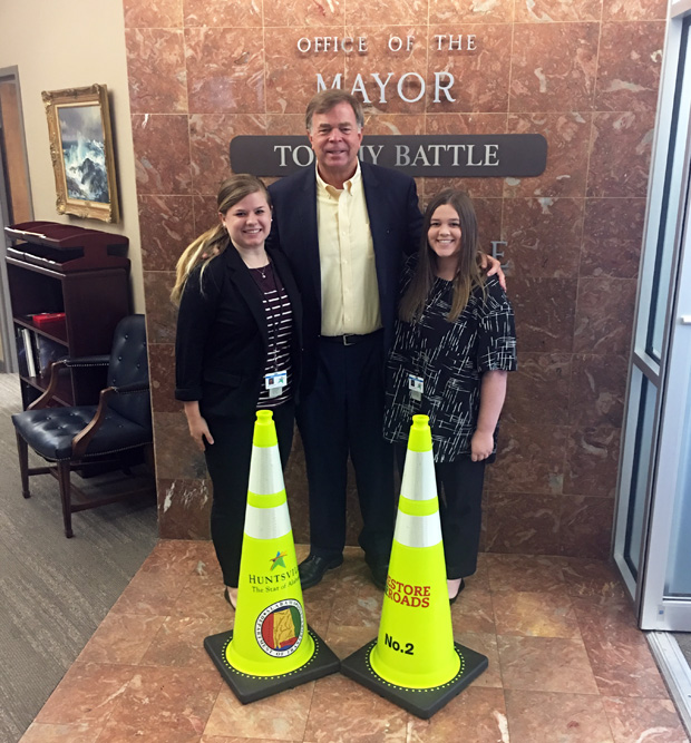 Molly Hollman and Ashley McCarley prepped two traffic cones for Mayor Battle to present to Governor Kay Ivey at a roads news conference and ribbon cutting.