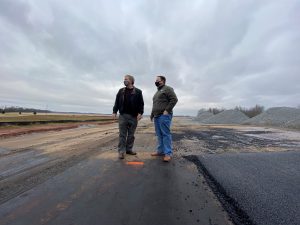 Mayor Tommy Battle and Economic Development Director Shane Davis stand on a section of unfinished Greenbrier Boulevard, looking to the west
