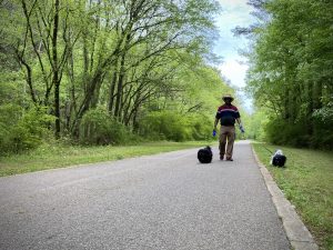 A man in a hat walks two small dogs on a walking trail in Hampton Cove