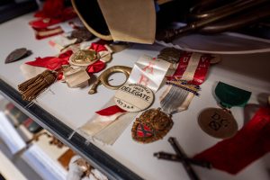 Old buttons and medals are displayed in a case. The most prominent says "Huntsville 1923 Delegate"