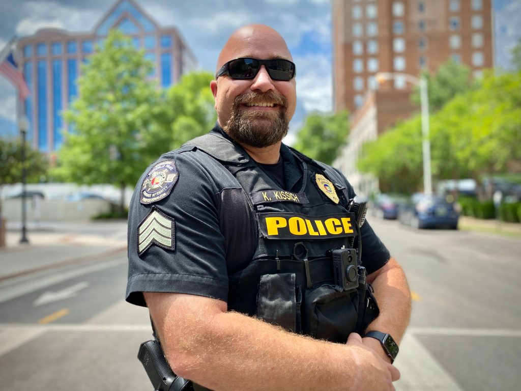 Sgt. Karl Kissich standing in downtown Huntsville smiling in his police uniform.
