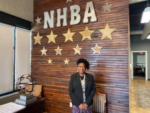 Judy Hardin stands in front of wall with NHBA letters and stars