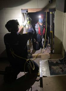 Firefighters work with flashlights during Heavy Rescue Team training. They are using struts to simulate a building collapse.
