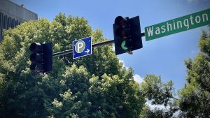 A blue way-finding sign is visible between two traffic lights on Washington Street in downtown Huntsville.