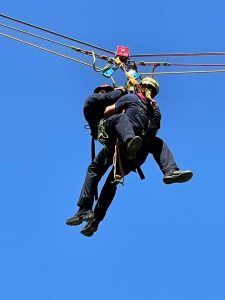 Two firefighters are suspended in mid-air during a roper training activity.