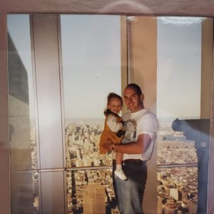 Mike Izzo holds his young daughter Brooke while standing on the observation deck of the World Trade Center. Manhattan can be seen in the background.