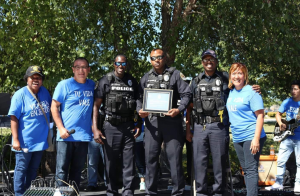 A group of volunteers pose for a photo with police officers at a park.