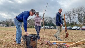 three adults assist in tree planting