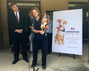 Huntsville Animal Services Director Dr. Karen Sheppard, joined by a cute pup, speaks at a 2018 event at the shelter as Mayor Tommy Battle looks on.
