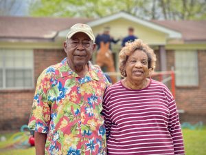 elderly couple arm-in-arm outside house
