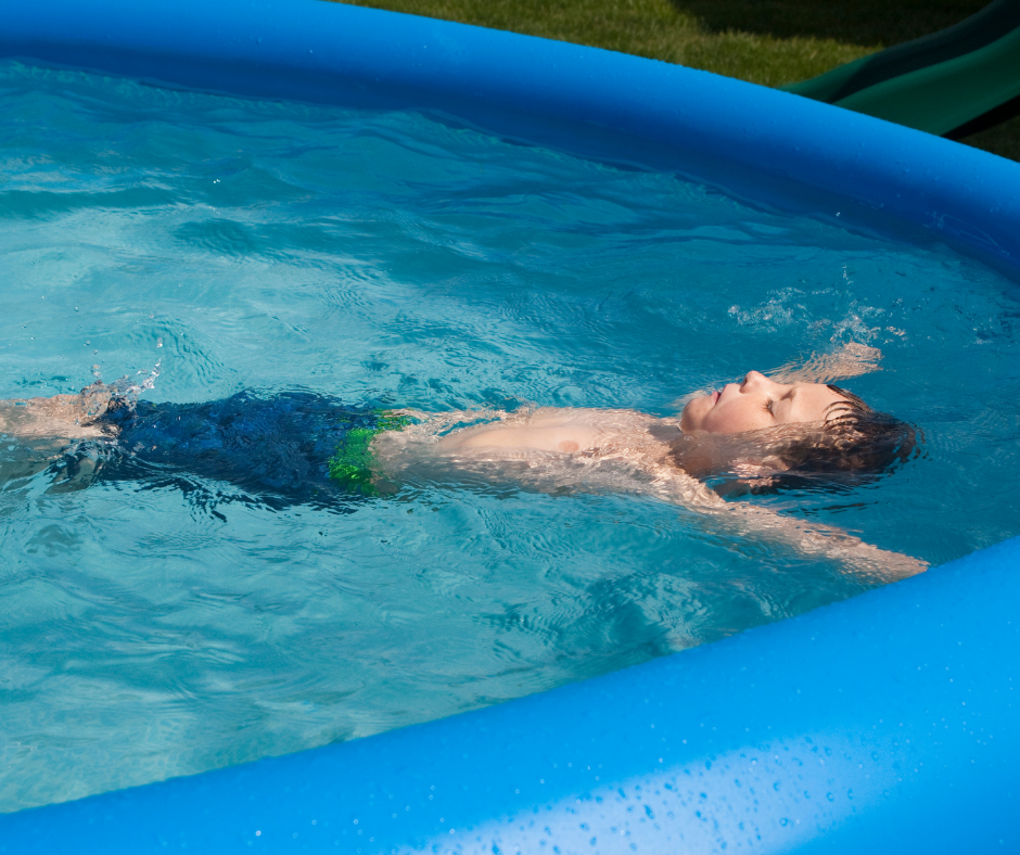 young boy in swim trunks floats on back in pool of water