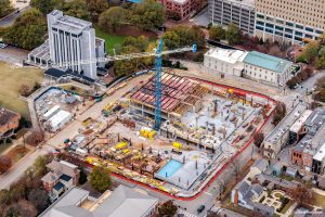 An aerial view of the ongoing construction of Huntsville City Hall in downtown Huntsville. A large crane is visible as are adjacent structures.
