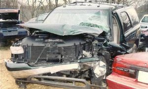 A totaled green SUV after being hit by a driver who was texting.