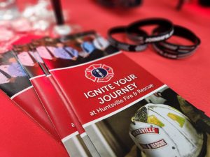 A recruitment pamphlet for Huntsville Fire & Rescue (HFR) lays on a table.