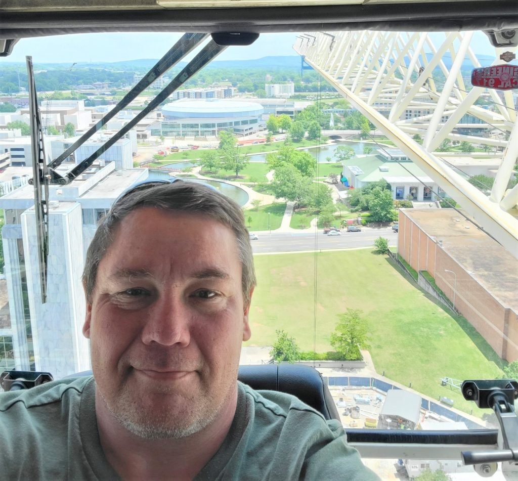 Crane operator Chuck Nash with the city skyline in the background as well as the boom jib from his crane.