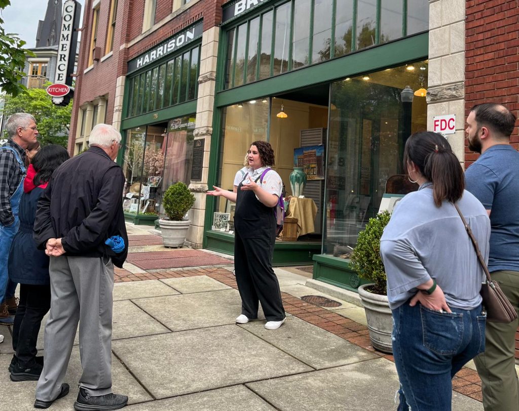Woman gives tour outside historic building with people watching