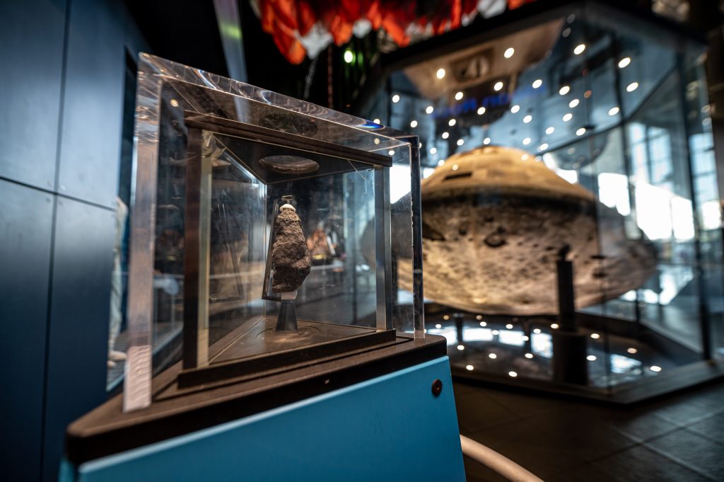 A display at the U.S. Space and Rocket Center shows a rock fragment behind thick glass.