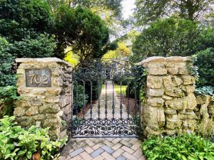 A pair of gates at a historic home in the Twickenham Historic District surrounded by green trees and brush.