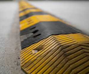 A yellow and black speed bump on a paved roadway.