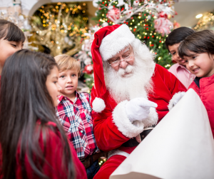 Santa checks his list surrounded by a diverse group of children.