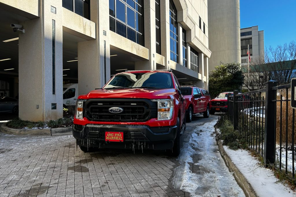 Huntsville Fire & Rescue trucks wait outside Huntsville Hospital. The trucks are red. There is visible ice on the lead truck.