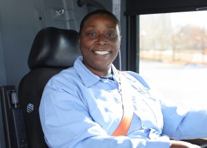 Kachina Edwards sits in a seat of a Huntsville Transit bus. She's wearing a blue uniform top.