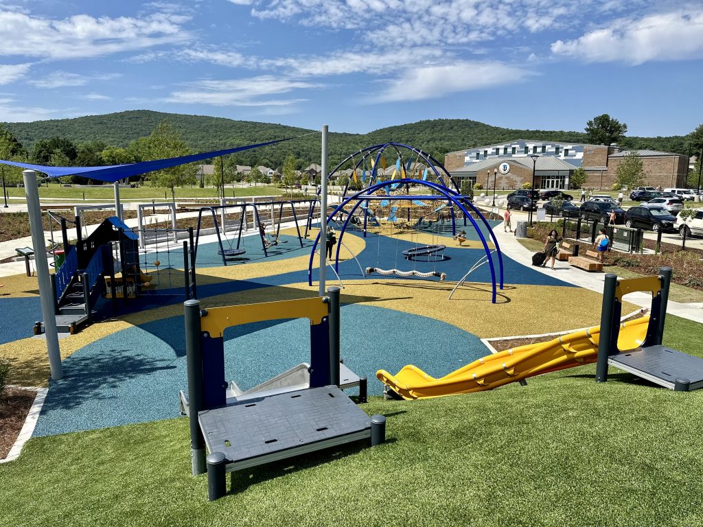 overhead view of playground equipment on blue and yellow surface with green mountains in background