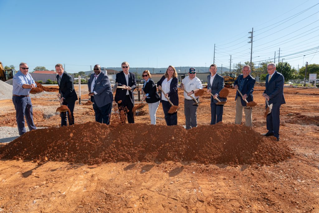 group of people with shovels standing on red dirt at groundbreaking ceremony