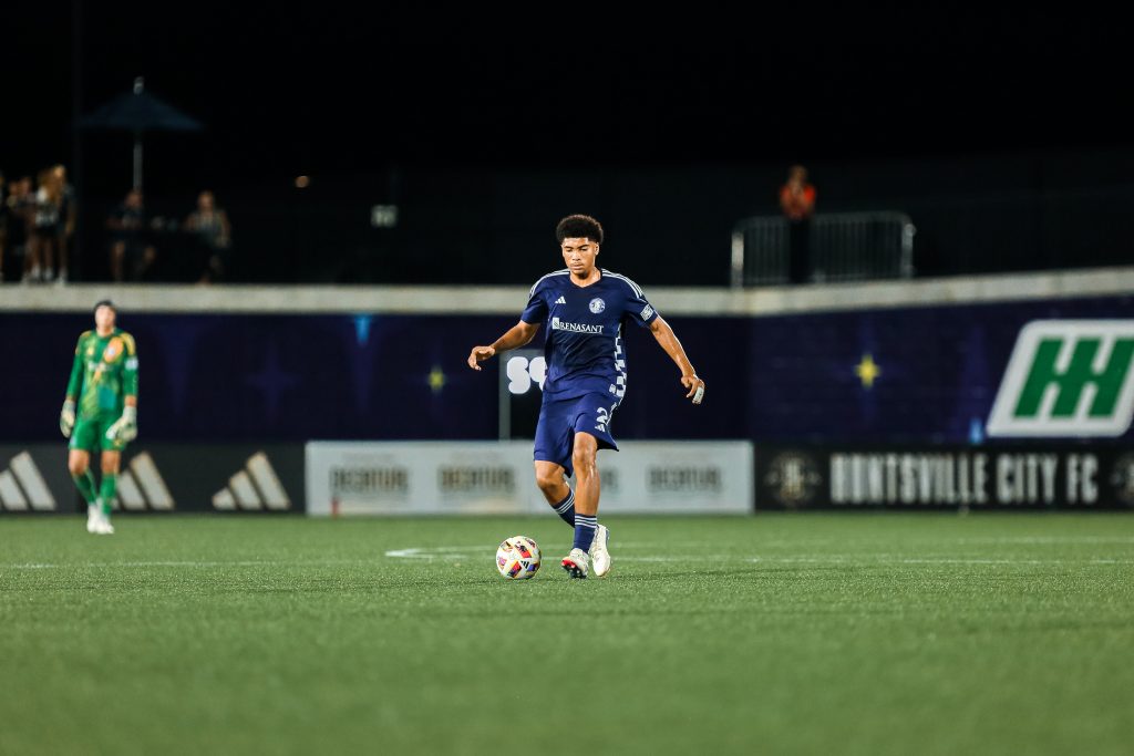 soccer player in blue uniform prepares to kick ball