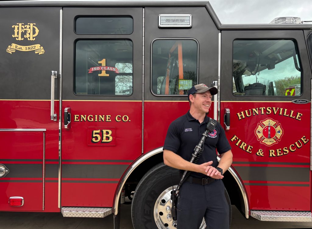 firefighter in blue uniform standing next to red fire truck
