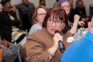 White woman with red hair speaking on microphone