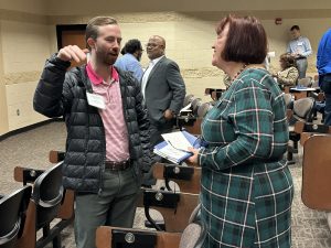 White woman and white man speaking in a classroom setting